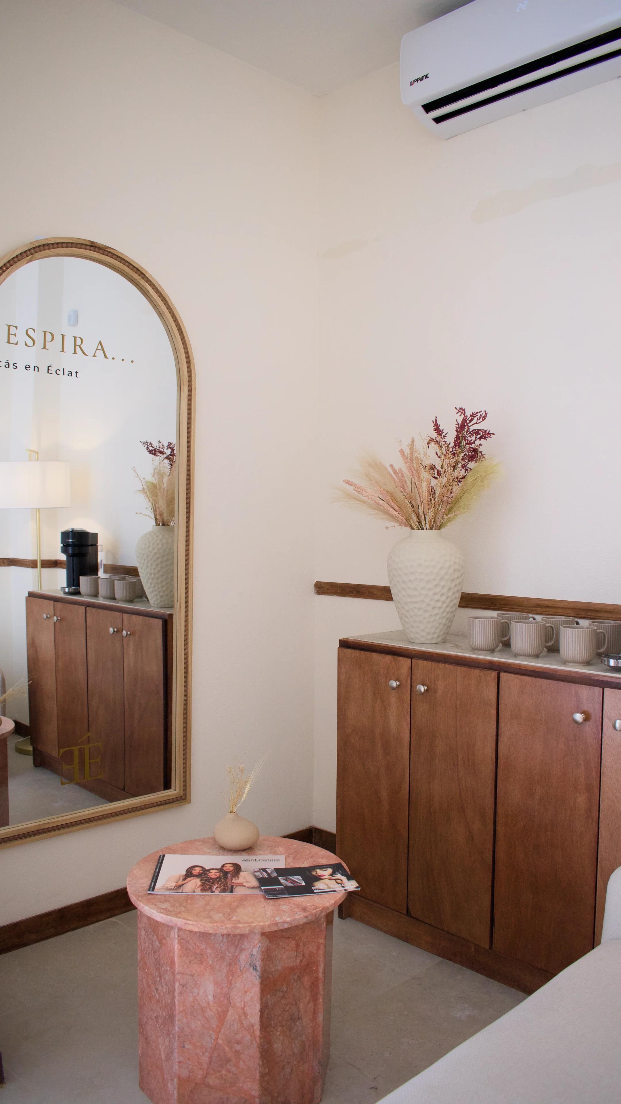 Recepción de Éclat Experience: mostrador en madera cálida, piedra travertino y sillones boucle