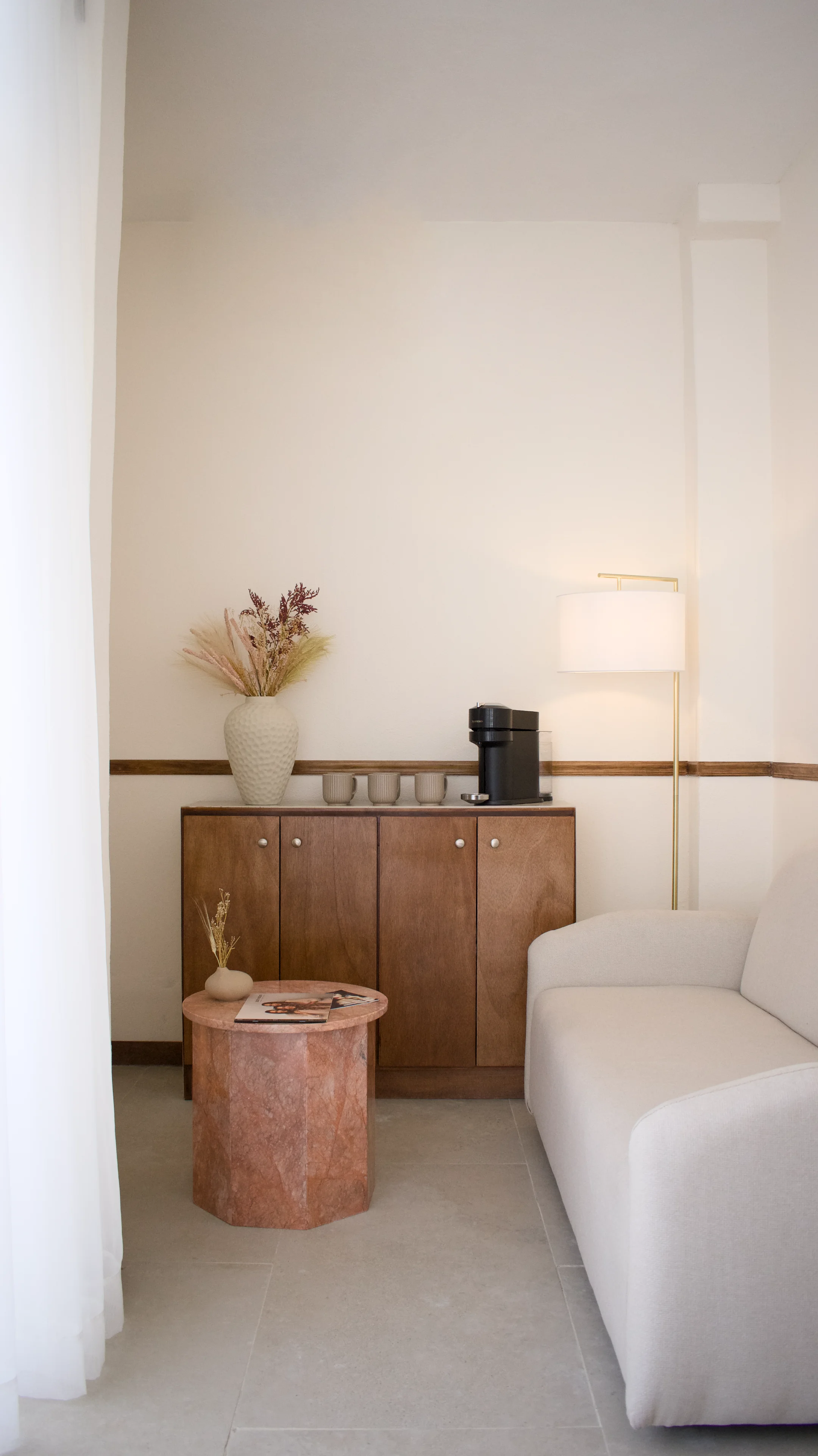Recepción de Éclat Experience: mostrador en madera cálida, piedra travertino y sillones boucle